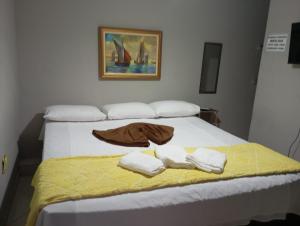 a bed with two towels and a blanket on it at Pousada Beira Mar in Matinhos