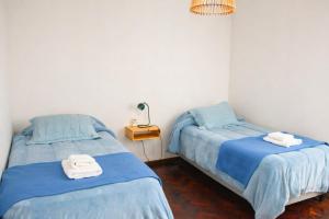 two beds in a room with blue sheets and towels at Arístides Azul in Mendoza
