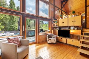 a living room with a tv and a chair and windows at Chalet 22 Bernau in Bernau im Schwarzwald