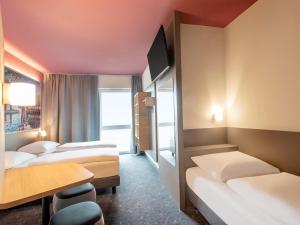 a hotel room with three beds and a table at B&B HOTEL Stralsund in Stralsund