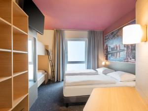 a hotel room with two beds and a window at B&B HOTEL Stralsund in Stralsund