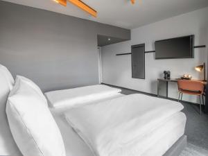 a hotel room with two beds and a flat screen tv at B&B HOTEL Stralsund in Stralsund