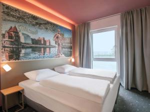 two beds in a hotel room with a picture on the wall at B&B HOTEL Stralsund in Stralsund +22 photos