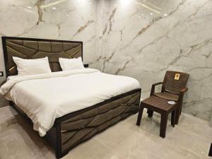 a bedroom with a bed and a wooden chair at Royal Guest House in Jammu +6 photos