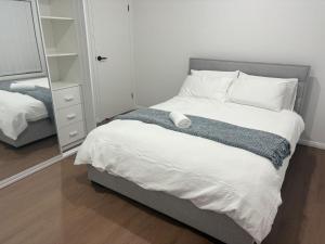 a bedroom with a large bed and a mirror at Second Home - A modern 4 Bedrooms House in Blacktown