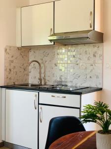 a kitchen with white cabinets and a sink and a table at Odyssée Résidence in Mahajanga