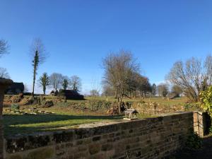 a stone wall with a bench in a field at Le Logis du GAST Chambre Taupe in Le Gast +1 photo