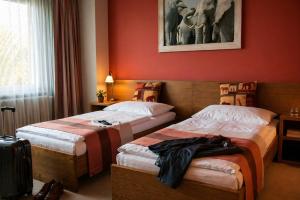 two beds in a hotel room with red walls at Afrika Hotel Frýdek-Místek in Frýdek-Místek