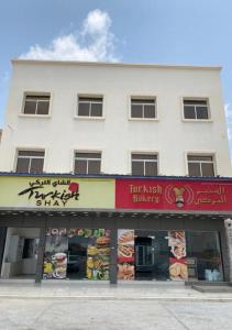 a white building with signs on the front of a store at Aknan Al Saada in Salalah