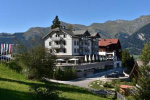 a large building on a hill with mountains in the background at The Alpina Mountain Resort in Tschiertschen