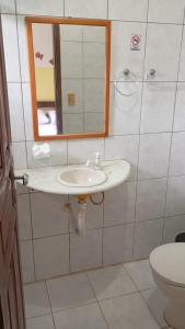 a bathroom with a sink and a mirror and a toilet at Pousada PauBrasil in Barra Grande