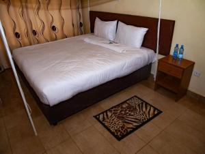 a bedroom with a bed with a wooden headboard and a table at Greenvale Hotel 1BR Along Kamiti Road in Kiambu +18 photos