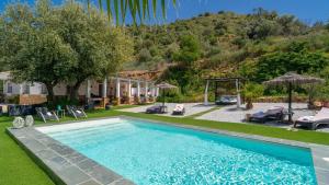 a swimming pool in a yard with chairs and umbrellas at Casa Corazón 44 Torrox by Ruralidays in Torrox