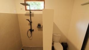 a bathroom with a shower with a toilet and a window at Nira Hostel Kuta Lombok in Kuta Lombok +16 photos