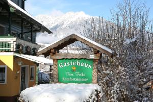 a sign in the snow in front of a building at Gästehaus Fuchs in Gröbming