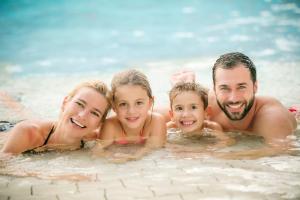 a family in the water in a swimming pool at H2O-Hoteltherme in Bad Waltersdorf