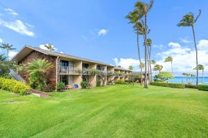 a house with palm trees in front of the ocean at Napili Shores D126 · NSD126 Cozy Studio Steps to Beach in Kahana