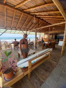 a woman in a bikini standing next to a surfboard at Hostal Rosa Mística in Montañita