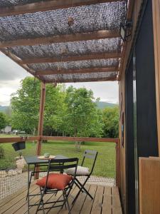 a patio with a table and chairs on a deck at Tiny House nature & détente, Vercors, terrasse, vue montagne in La Motte-Fanjas