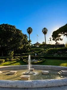 a fountain in the middle of a park with palm trees at Margherita Rooms in Catania