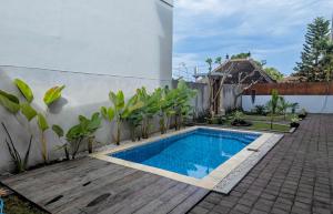 a swimming pool in a garden next to a wall at Patera Living in Sempidi +5 photos
