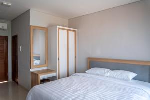 a bedroom with a white bed and a mirror at Patera Living in Sempidi