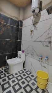a bathroom with a toilet and a yellow bucket at Jay shree Kedar room in Ujjain