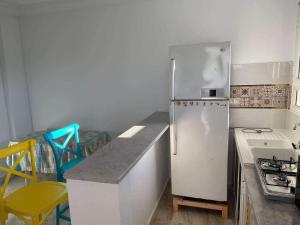 a kitchen with a white refrigerator and some chairs at Haouaria PANTELLERIA in Sidi Amor