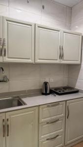 a kitchen with white cabinets and a tea kettle on the counter at ريف سويت للشقق المخدومة in Al Namas