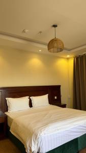 a bedroom with a large bed with a wooden headboard at ريف سويت للشقق المخدومة in Al Namas