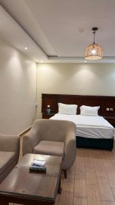 a bedroom with a bed and a couch and a table at ريف سويت للشقق المخدومة in Al Namas