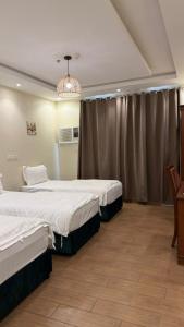 a hotel room with two beds and a chandelier at ريف سويت للشقق المخدومة in Al Namas +3 photos