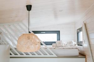 a white room with a bed and a chandelier at Tiny Seaside - Kegnæs in Østerby