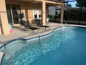 a large swimming pool with chairs and a house at Pool Home in Englewood