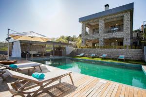 a swimming pool with two lounge chairs and a building at Trioda Kazdağları in Ayvacık
