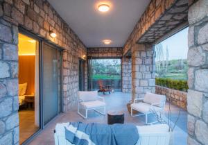 a stone walled patio with white chairs and a table at Trioda Kazdağları in Ayvacık