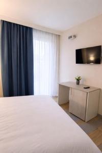 a bedroom with a bed and a desk and a television at Il Ritrovo Rooms in Petralia Sottana
