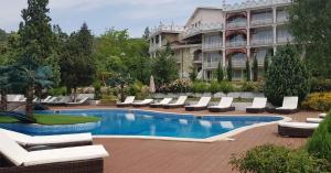 a hotel with a swimming pool with lounge chairs and a building at Hotel Elit Palace and SPA in Balchik