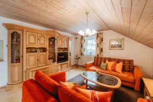 a living room with orange furniture and a wooden ceiling at Ferienwohnung Pietzavka in Wiesenfelden