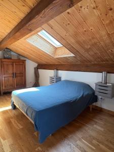 a bedroom with a blue bed in a attic at Les Combes Claires in Saint-Julien-Labrousse