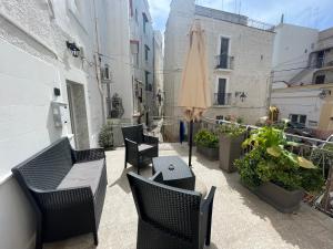 a patio with chairs and an umbrella and plants at Casa Buena Vida (locazione ad uso turistico) in Monopoli