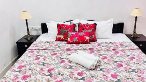 a bed with red and white pillows and a bedspread with flowers at HOTEL SHREE JMM s14 near by in Udaipur
