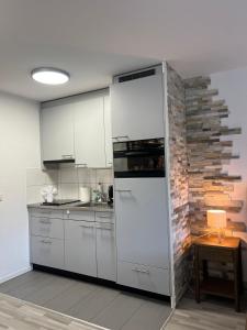 a kitchen with white cabinets and a brick wall at Rawda Ferien Wohnung in Interlaken
