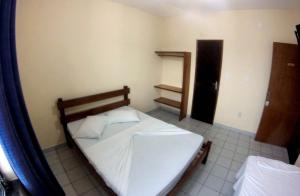 a bedroom with a white bed in a room at Hotel Caiçara in Praia Grande +4 photos