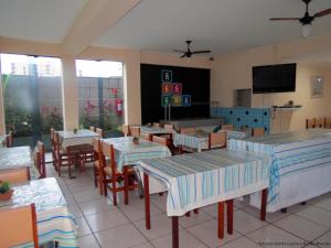 a restaurant with tables and chairs and a flat screen tv at Hotel Caiçara in Praia Grande