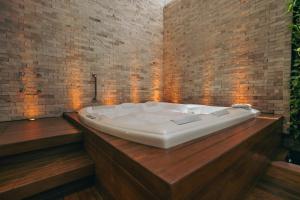 a bath tub in a room with a brick wall at Luna Blu Concept in Curitiba