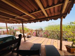 a large wooden deck with chairs and a roof at Villa Mouna in Poponguine