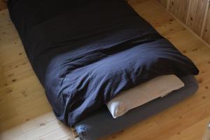 a blue bed with two pillows on a wooden floor at Lotus Retreat ロータスリトリート 高知空港から車で30分 山のふもとの一棟貸しコテージ in Kami