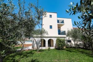 a white house with trees in front of it at Villa Vita Mare in Preko