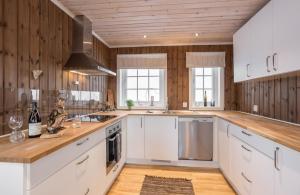 a kitchen with white cabinets and wooden walls at Rauland Feriesenter in Rauland +18 photos